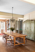 Custom-made dining table with modern chairs and antique hand painted cabinet in dining room