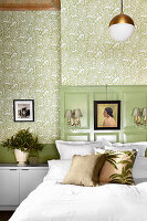Double bed with pillows in front of green coffered walls and green patterned wallpaper in the bedroom