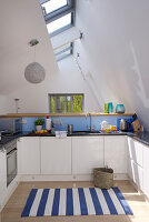 Blaue Rückwand in moderner, weißer Küche mit blau-weiß gestreiftem Teppich