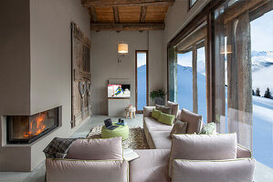 Elegant living room in light tones with panoramic views of snowy mountain landscape