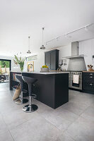 Elegante offene Küche mit dunkelgrauen Einheiten und Steinfliesen