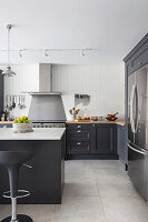 Elegante offene Küche mit dunkelgrauen Einheiten und Steinfliesen