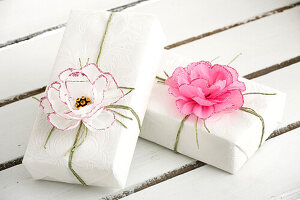 Geschenkverpackung mit DIY-Papierblüten dekoriert