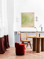 Runder Esstisch mit Stuhl und roter Sitzpouf in hohem Raum mit bodenlangem Vorhang