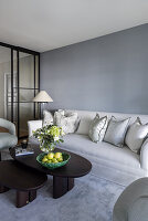 Elegantes Wohnzimmer in Grautönen, dunkler Couchtisch