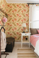 Schlafzimmer mit Blumentapete, Stiller Diener und Holztruhe vor der Wand