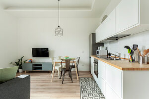 White kitchenette with wooden worktop and small dining area in the living room