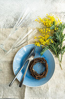 Festive table setting for Easter holiday dinner with bright yellow mimosa flowers on concrete table