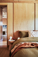 Doppelbett und Nachttisch im Schlafzimmer mit Holzpaneelen