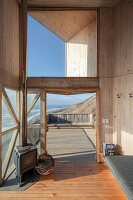 Blick vom Wohnbereich auf Eingang und Terrasse eines Holzhauses mit Meerblick