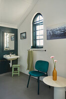 Badezimmer mit Bogenglasfenster, Waschbecken, Stuhl und dekorativen Blumen