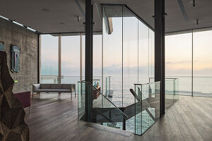 Central staircase in formal living room with concrete wall and floor to ceiling windows