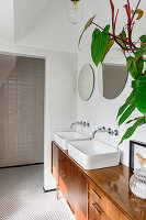 Badezimmer mit Doppelwaschbecken auf Holzunterschrank und Spiegeln