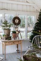 Winterliche Dekoration auf Holztisch mit Tannenbaum, Rentierfigur und Kerzen