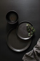 Black ceramic plates and bowl on black background