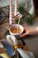 Cup of coffee in hand on a table set with fir branches and candles