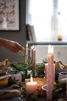 Lighting candles on a festively laid table with fir branches