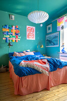 Colourful wall hanging above double bed in bedroom with blue walls