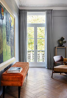 Orangefarbene Sitzbank mit Samtbezug, darüber Kunstwerk in formalem Wohnzimmer mit französischer Tür