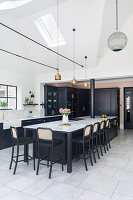 Modern kitchen with black cabinets, dining area and copper-coloured pendant lights