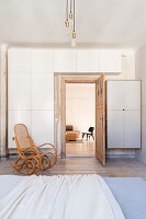 Bedroom with white wardrobes and rocking chair, passageway to adjoining room
