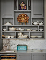 Open grey shelves with crockery and a clock in a kitchen