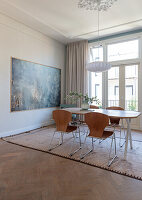 Dining area with wooden table, brown chairs and modern artwork
