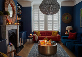 Velvet sofas and fireplace in a living room with blue walls and Christmas decorations