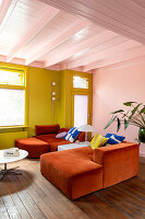 Living room with orange sofas, green and pink wall and houseplant