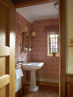 Traditionelles Badezimmer mit gemusteter Tapete und Holzdetails