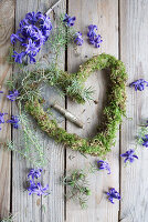 Heart-shaped wreath made of moss on a wooden background, surrounded by hyacinth flowers