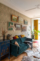 Velvet sofa in front of floral patterned wallpaper and picture wall in the living room