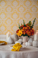 Herbstlicher Blumenstrauß und Kürbisse aus Keramik auf Tisch