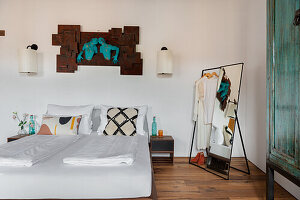 Bedroom with double bed, wall art and clothes rack with mirror