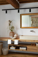 Modern bathroom with wooden furniture and large wall mirror in gold frame