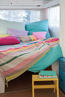 Colorful bed linen and cushions on a bed in the camper