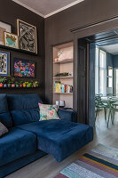 Living room with blue sofa, dark-painted walls and pictures on the wall