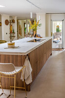 Large wooden kitchen island with white marble worktop and bar stool