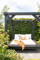 Black garden pavilion with day bed and decorative pillows