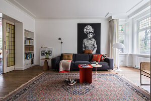 Living room with dark grey sofa, oriental rug and portrait art on the wall