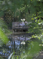 Wooden footbridge with seating area by the pond in the summer garden