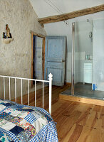 Rustikales Schlafzimmer mit Natursteinwand und moderner Duschkabine