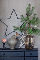 Chest of drawers decorated for Christmas with vases, stars, pine branches and candles