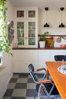 Dining room with retro furniture and black and white chequered floor, kitchen in the background