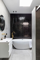 Modern bathroom with free-standing bathtub and black herringbone tiled walls