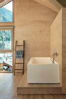 Modern bathroom with free-standing, angular bathtub and Alpine-style wood panelling