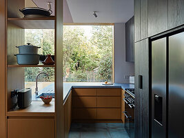 Modern, U-shaped kitchen with built-in appliances and views of the garden