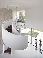 Spiral staircase with glass railings in a bright entrance area