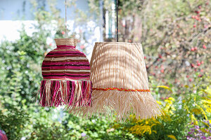 Two hanging raffia lamps in the garden