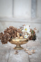 Winter still life with hydrangeas, Christmas roses and gold glass decoration